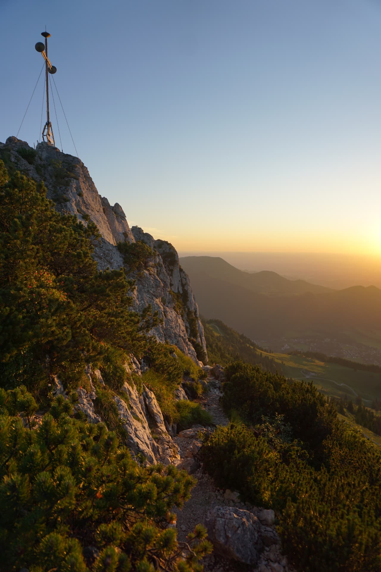 Gipfelkreuz im Chiemgau im Sonnenaufgang über dem Tal