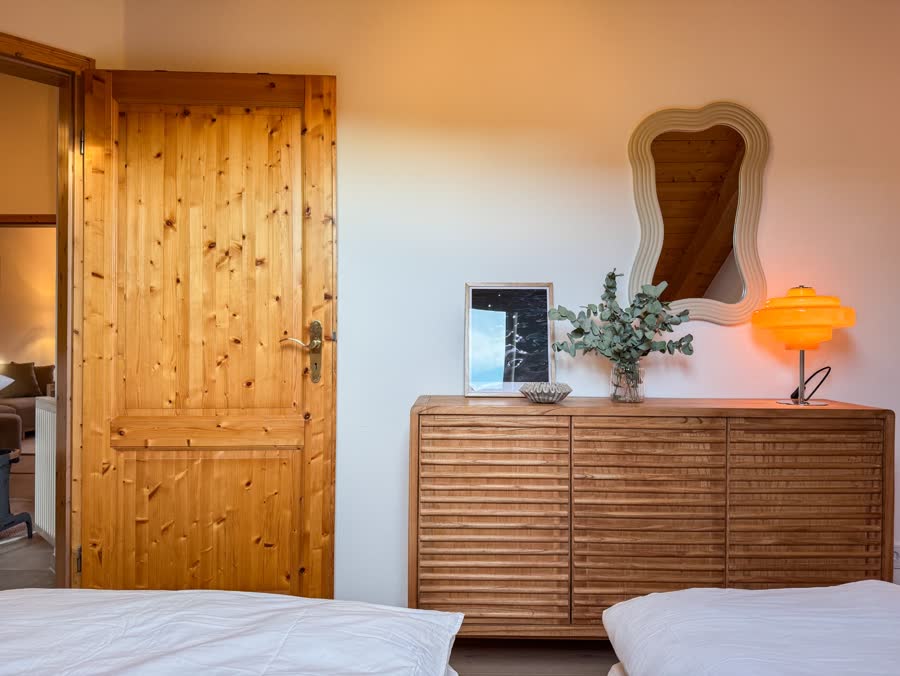 Sideboard mit Wellenspiegel und oranger Vintage-Lampe im Schlafzimmer